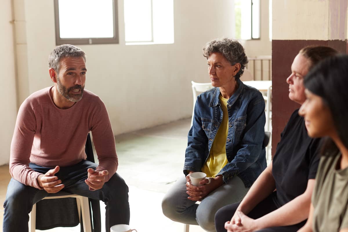 Angehörigenarbeit in der Karl Immanuel Küpper-Stiftung, ein Therapeut sitzt mit Erwachsenen zusammen