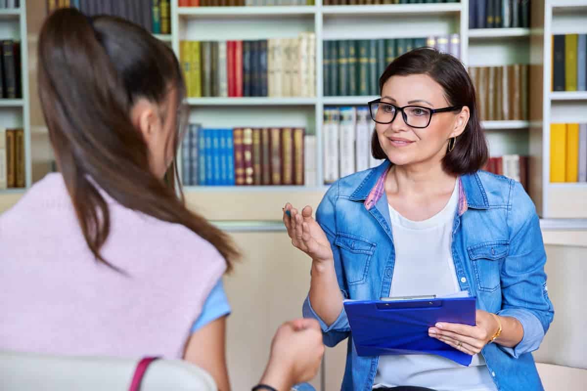 Psychologisch-Therapeutischer Fachdienst der Karl Immanuel Küpper-Stiftung, Therapeutin sitzt mit Jugendlicher zusammen und erklärt.